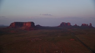 AX133_233 - 5.5K aerial stock footage of flying by highway with view of mesa, buttes in Monument Valley, Utah, Arizona, twilight