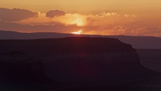 AX134_002E - 5.5K aerial stock footage of flying by setting sun, seen from a mesa, Monument Valley, Utah, Arizona, sunset
