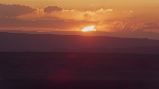 AX134_005E - 5.5K aerial stock footage of flying by sun setting behind mesas in Monument Valley, Utah, Arizona, sunset