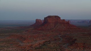 AX134_014E - 5.5K aerial stock footage of flying by buttes and hazy desert valley, Monument Valley, Utah, Arizona, twilight