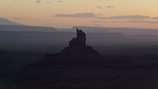 AX134_026E - 5.5K aerial stock footage of flying by Big Indian Butte and Sentinel Mesa, Monument Valley, Utah, Arizona, twilight