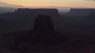 AX134_056E - 5.5K aerial stock footage of flying by several buttes in thick haze, Monument Valley, Utah, Arizona, twilight
