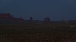 AX134_074E - 5.5K aerial stock footage of flying by small town and buttes in Monument Valley, Utah, Arizona, night