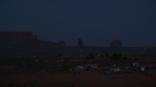 AX134_075 - 5.5K stock footage aerial video of flying by small town and buttes in Monument Valley, Utah, Arizona, night