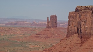 AX135_037E - 5.5K aerial stock footage of passing by East Mitten Butte, reveal West Mitten Butte, Monument Valley, Utah, Arizona