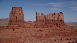 AX135_046 - 5.5K stock footage aerial video of flying by three buttes in a desert valley, Monument Valley, Utah, Arizona