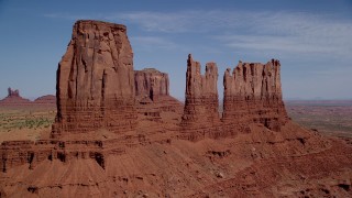 AX135_047 - 5.5K aerial stock footage of passing three buttes in a desert valley, Monument Valley, Utah, Arizona