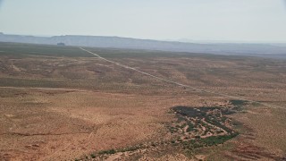 AX135_070E - 5.5K aerial stock footage of flying toward Highway 163 in desert valley, Monument Valley, Utah, Arizona