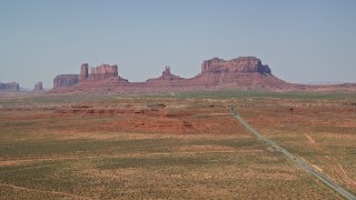 AX135_079E - 5.5K aerial stock footage of a wide view of Highway 163 leading to desert buttes, Monument Valley, Utah, Arizona