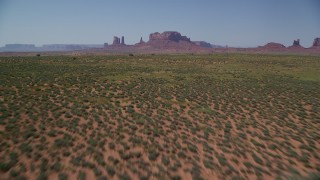 AX135_093 - 5.5K stock footage aerial video of flying low over desert, tilt to reveal buttes in the distance, Monument Valley, Utah, Arizona