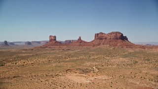 AX135_105E - 5.5K aerial stock footage of an approach to buttes across a desert valley, Monument Valley, Utah, Arizona