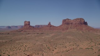 AX135_106 - 5.5K stock footage aerial video of an approach to buttes across a desert valley, Monument Valley, Utah, Arizona