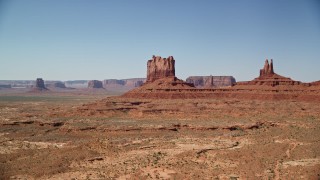 AX135_108E - 5.5K aerial stock footage of flying by buttes with a view of the desert valley, Monument Valley, Utah, Arizona
