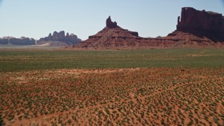 AX135_124 - 5.5K aerial stock footage tilt from desert to reveal and approach Rooster Rock in Monument Valley, Utah, Arizona