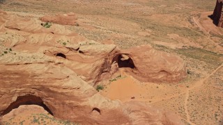 AX135_180 - 5.5K aerial stock footage of orbiting a rock arch near caves, rock formations, Monument Valley, Utah, Arizona