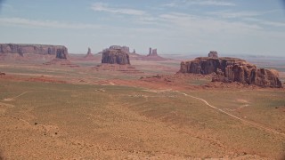 AX136_019E - 5.5K aerial stock footage of numerous buttes in a hazy desert valley, Monument Valley, Utah, Arizona