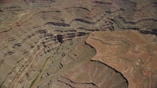 AX136_058E - 5.5K aerial stock footage of passing by San Juan River in a deep desert canyon, Navajo Nation Reservation, Utah, Arizona
