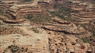 AX136_062 - 5.5K aerial stock footage of flying by mesa cliffs and scattered vegetation, Cedar Mesa, Utah