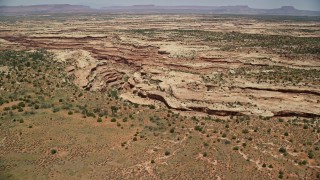 AX136_068E - 5.5K aerial stock footage of passing a canyon through a mesa, Cedar Mesa, Utah