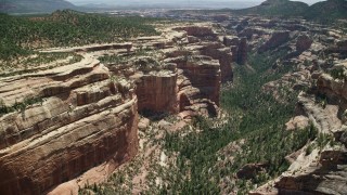 AX136_142E - 5.5K aerial stock footage of flying by and descending into Arch Canyon, Utah