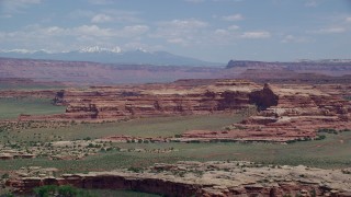 AX136_223 - 5.5K aerial stock footage of desert rock formations and green valleys, Canyonlands National Park, Utah