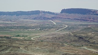AX137_001E - 5.5K aerial stock footage of passing by Highway 191 through desert valley, Moab, Utah