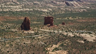 AX137_065E - 5.5K aerial stock footage of a close orbit of Balanced Rock and Arches Scenic Drive, Arches National Park, Utah