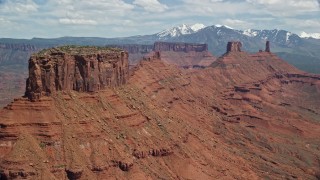 AX137_093E - 5.5K aerial stock footage of flying by a butte with Castleton Tower in the background, Moab, Utah