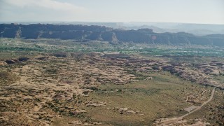 AX138_036E - 5.5K aerial stock footage approach small desert town from rock formations, Sand Flats Recreation Area, Moab, Utah