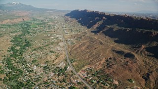 AX138_041E - 5.5K aerial stock footage of a highway running through a small desert town, Moab, Utah