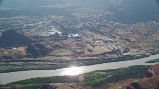 AX138_055E - 5.5K aerial stock footage of Intrepid Potash factory on a bank of the Colorado River, Moab, Utah