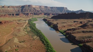 AX138_063E - 5.5K aerial stock footage follow Colorado River toward a mesa, Moab, Utah