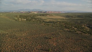 AX138_240E - 5.5K aerial stock footage of flying over desert, approaching rocky hill, Moab, Utah