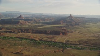 AX138_260E - 5.5K aerial stock footage slowly approach North Six-Shooter Peak, South Six-Shooter Peak in hazy valley, Moab, Utah