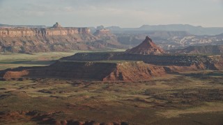 AX138_262E - 5.5K aerial stock footage of passing by South Six-Shooter Peak in a hazy desert valley, Moab, Utah