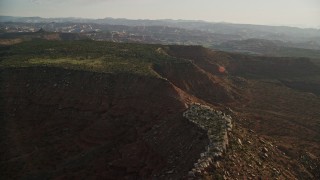 AX138_275E - 5.5K aerial stock footage of passing by desert mesa and box canyon, Moab, Utah