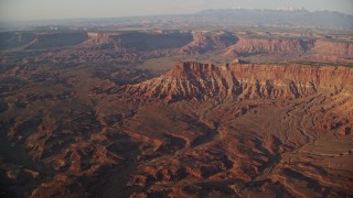 AX138_338E - 5.5K aerial stock footage of approaching Lockhart Canyon and mesas, Moab, Utah, sunset