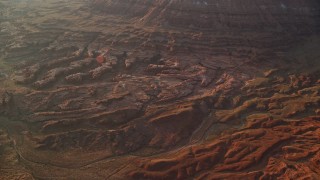 AX138_347 - 5.5K aerial stock footage of flying by rock formations and box canyons in hazy Lockhart Canyon, Moab, Utah, sunset