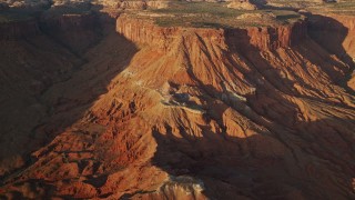 AX138_348E - 5.5K aerial stock footage of passing by cliffs in Lockhart Canyon, Moab, Utah, sunset