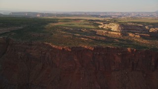 AX138_350E - 5.5K aerial stock footage approach and fly over dirt road near rock formations on Hatch Point, Moab, Utah, sunset