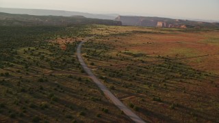 AX138_354 - 5.5K aerial stock footage of flying by Hatch Point Road and a dirt road intersection, Moab, Utah, sunset