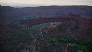 AX138_395E - 5.5K aerial stock footage of approaching rock formations near Dry Mesa cliffs, Moab, Utah, sunset