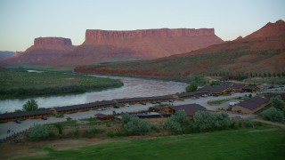 AX138_402 - 5.5K stock footage aerial video of approaching Red Cliffs Lodge by the Colorado River, Moab, Utah, sunset