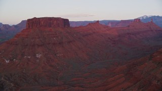 AX138_407E - 5.5K aerial stock footage of approaching two buttes and Castleton Tower, Moab, Utah, sunset