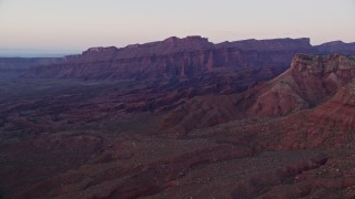 AX138_428E - 5.5K aerial stock footage of an approach to rock formations and mesa, Fisher Towers, Utah, sunset
