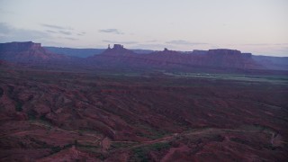 AX138_449E - 5.5K aerial stock footage of giant desert buttes across valley, Moab, Utah, twilight