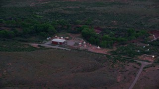 AX138_453 - 5.5K aerial stock footage of approaching a small desert museum with teepees, Moab, Utah, twilight
