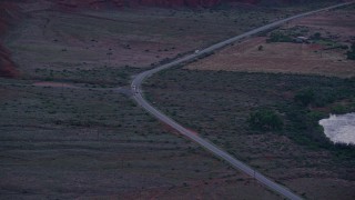 AX138_457E - 5.5K aerial stock footage track SUV, two sedans on State Route 128, Moab, Utah, twilight