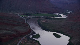 AX138_459E - 5.5K aerial stock footage of approaching Red Cliffs Lodge and Colorado River, Moab, Utah, twilight