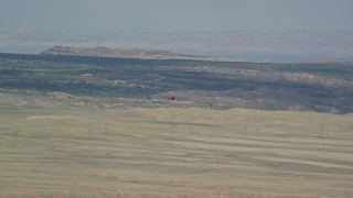 AX139_014E - 5.5K aerial stock footage of tracking a skydiver landing in a field, Canyonlands Field, Utah